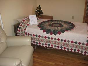 A resident room, with pretty quilt on the bed and comfortable chair at its side